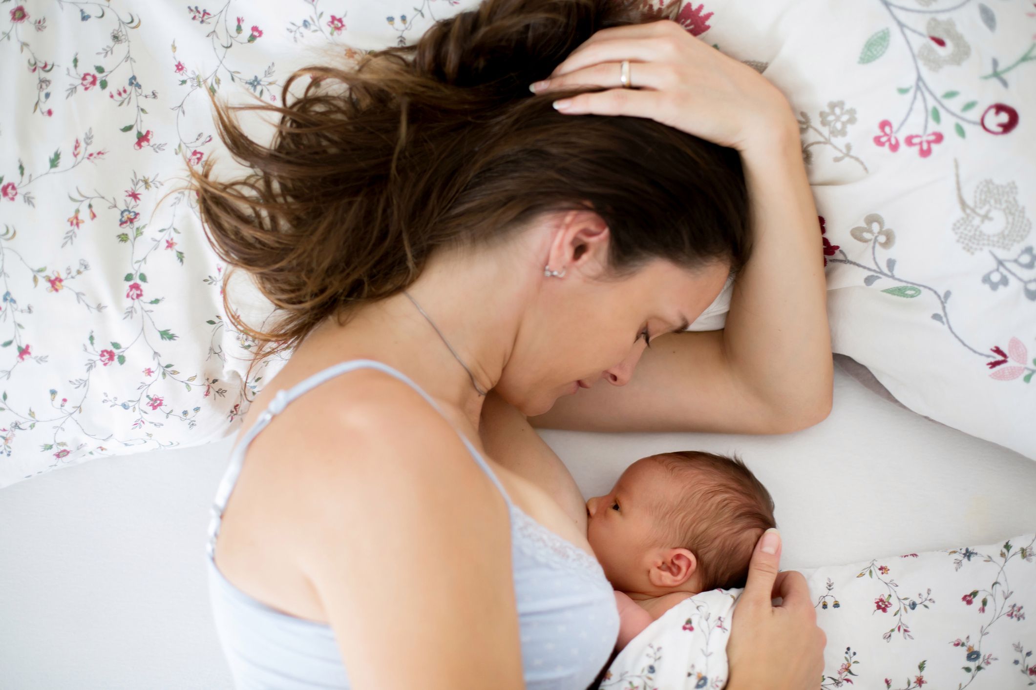 Young mother breastfeeds her baby, holding him in her arms and smiling from happiness 