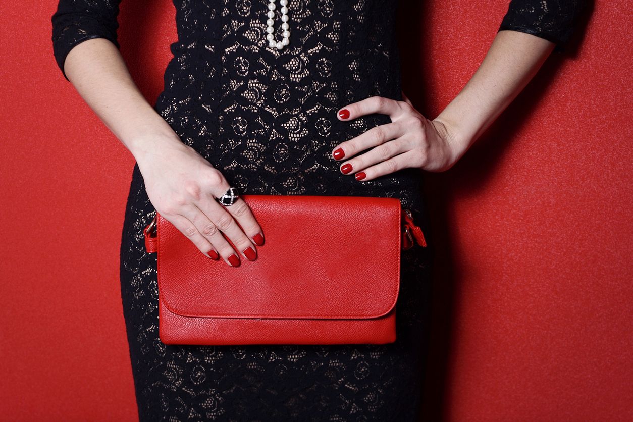 Fashionable woman with a red bag in her hands and black evening dress 