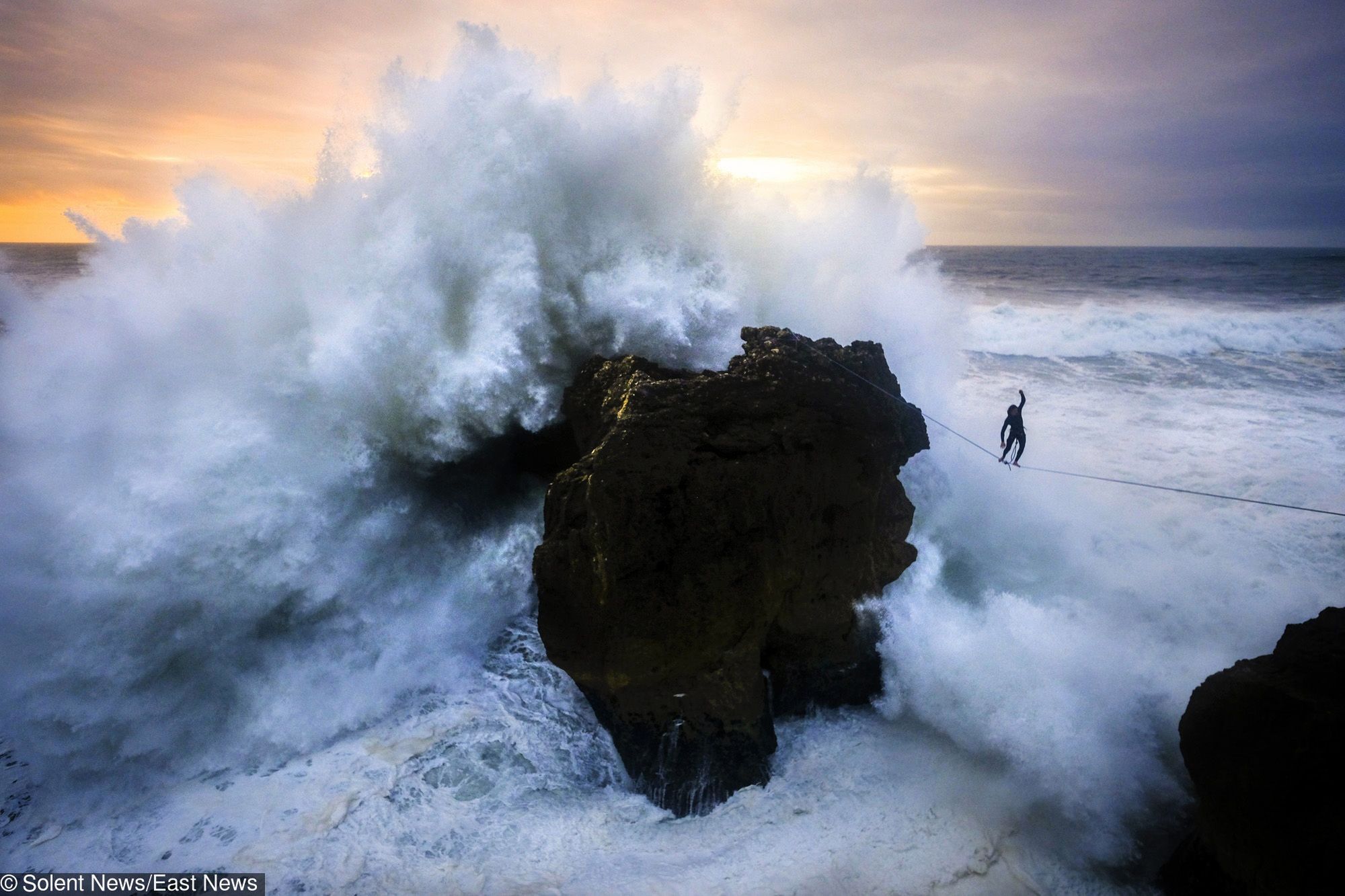 A daredevil athlete walks across a slackline suspended 50ft in the air as ferocious waves crash around him.  Andrey Karr took on the daring 100ft-long line as the huge waves engulfed the rocks his webbing was tied to.  Adventure photographer Aidan Williams was able to capture the moment the dramatic conditions got the better of Mr Karr and flung him, leaving him dangling from the slackline.  The photographs were taken in Nazare, Portugal, an area popular with surfers thanks to its huge waves.  SEE OUR COPY FOR DETAILS.  Please byline: Aidan Williams/Solent News  ? Aidan Williams/Solent News & Photo Agency UK +44 (0) 2380 458800 