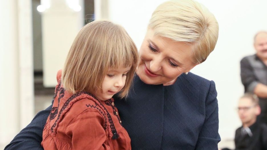 Agata Duda trzyma na rękach dziewczynkę chorą na rdzeniowy zanik mięśni