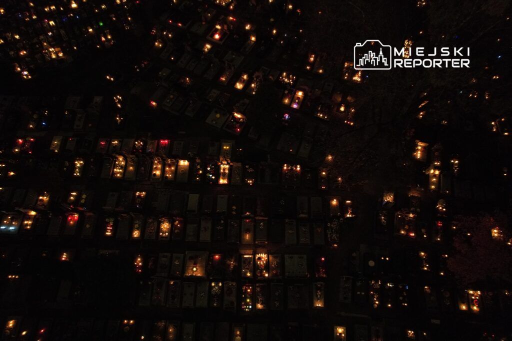 Cmentarz oświetlony setkami zniczy w noc, tworzących atmosferę zadumy i refleksji.