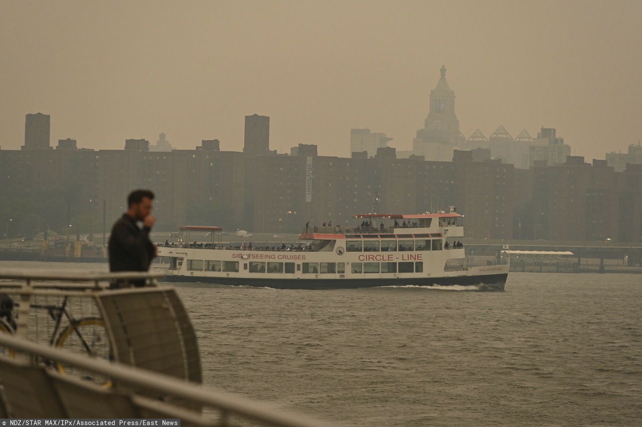 Prom Circle Line przepływa obok mostu Williamsburg, gdy panoramę Manhattanu spowija dym z pożarów w Kanadzie, 6 czerwca 2023 r. w Nowym Jorku.