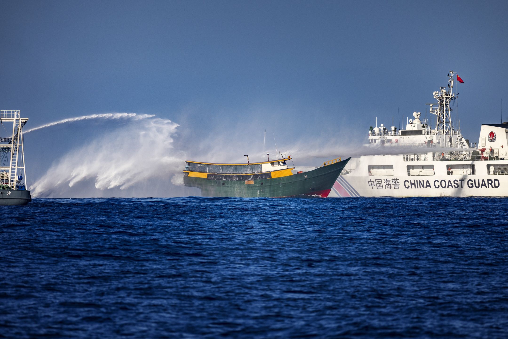 SOUTH CHINA SEA - MARCH 05: Chinese Coast Guard ships fire water cannons at Unaizah May 4, a Philippine Navy chartered vessel, conducting a routine resupply mission to troops stationed at Second Thomas Shoal, on March 05, 2024 in the South China Sea. Philippine and Chinese vessels collided in the high seas, leaving four Filipinos with minor injuries after a supply vessel's windshield was shattered by water cannons, the Philippines said. The incidents happened as the Philippines was conducting a routine resupply mission to troops stationed aboard BRP Sierra Madre, a grounded Navy ship that serves as the country's outpost in Second Thomas Shoal (locally called Ayungin Shoal). (Photo by Ezra Acayan/Getty Images)
