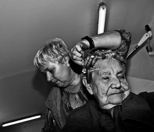 Przedstawiamy cykl zdjęć pt. „Hair”, który pojawił się w maju 2014 roku w magazynie LFI. Jens Juul często mijał stary salon fryzjerski, gdzie starsze panie dbają o swoje fryzury i tętni lokalne życie społeczne. Pewnego dnia fotograf pojawił się tam z aparatem i zapytał czy może wykonać zdjęcia. Od tego czasu Jens odwiedził wiele salonów fryzjerskich zafascynowany ich specyfiką, gdzie ludzie pozwalają właściwie nieznanej osobie zbliżyć się do siebie naprawdę blisko i kształtować wizerunek, który prezentują światu.