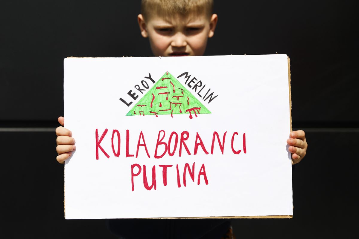 A boy holds a banner calling Leroy Merlin a collaborator of Vladimir Putin while demonstrating in front of a store and calling for a boycott of the brand. Andrychow, Poland on April 23, 2022. Leroy Merlin, Auchan and Decathlon chain stores, belonging to the same French holding, have not stopped operating in Russia after the invasion on Ukraine. (Photo by Beata Zawrzel/NurPhoto via Getty Images)