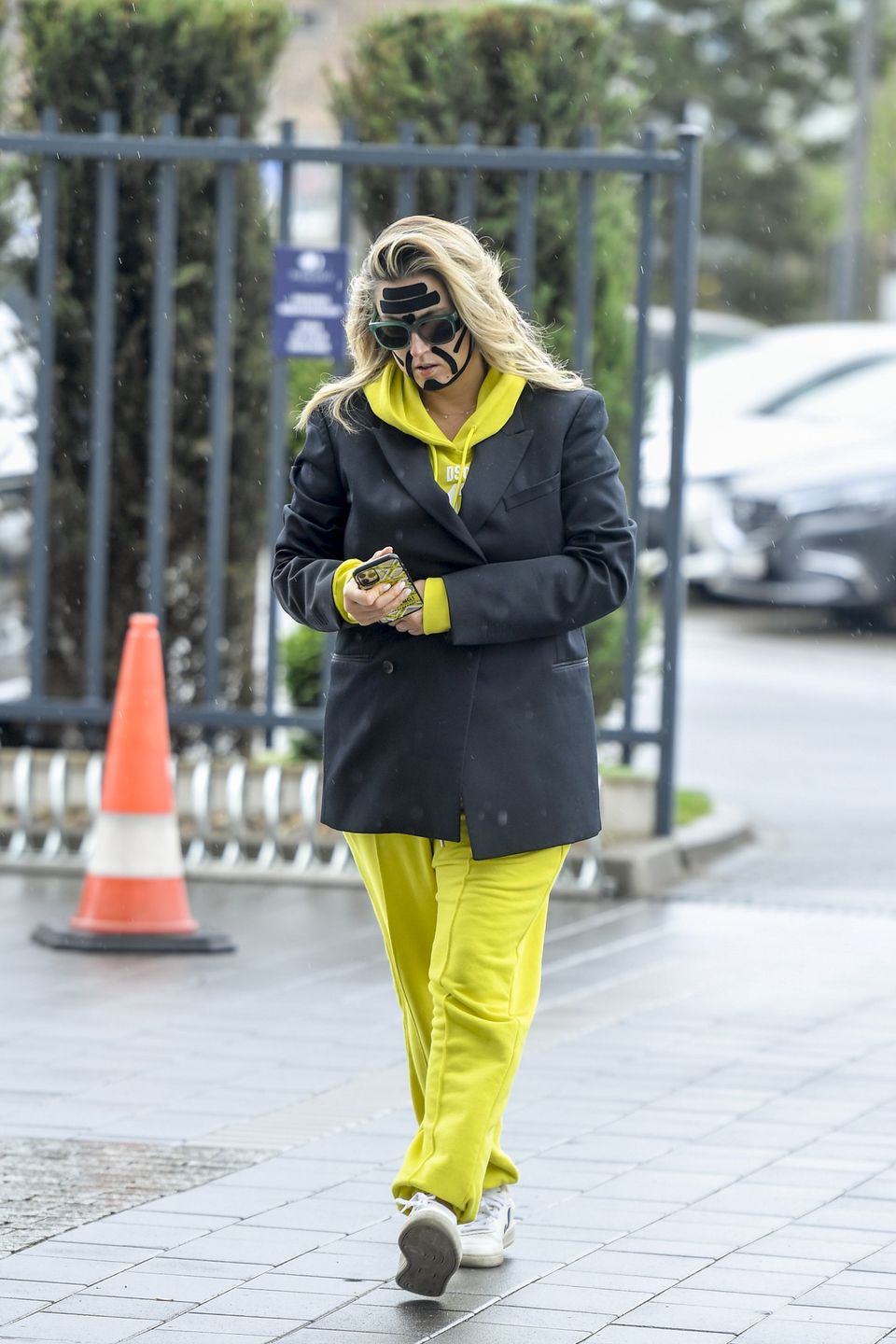 Karolina Szostak wpatrzona w telefon mknie do pracy z taśmami na twarzy 