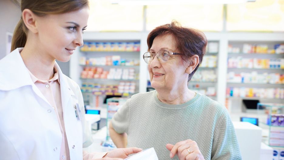 Female pharmacist assisting senior woman