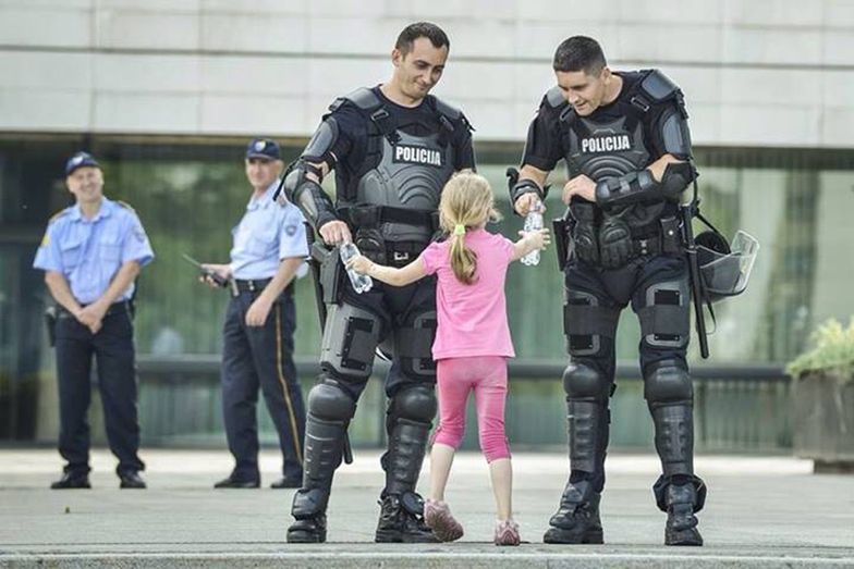 Bośnia, 2013. Dziewczynka daje butelki z wodą policjantom.