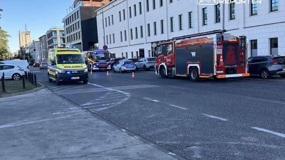 Karetka pogotowia i wóz strażacki blokują ulicę, podczas gdy służby ratunkowe interweniują w miejskim otoczeniu.