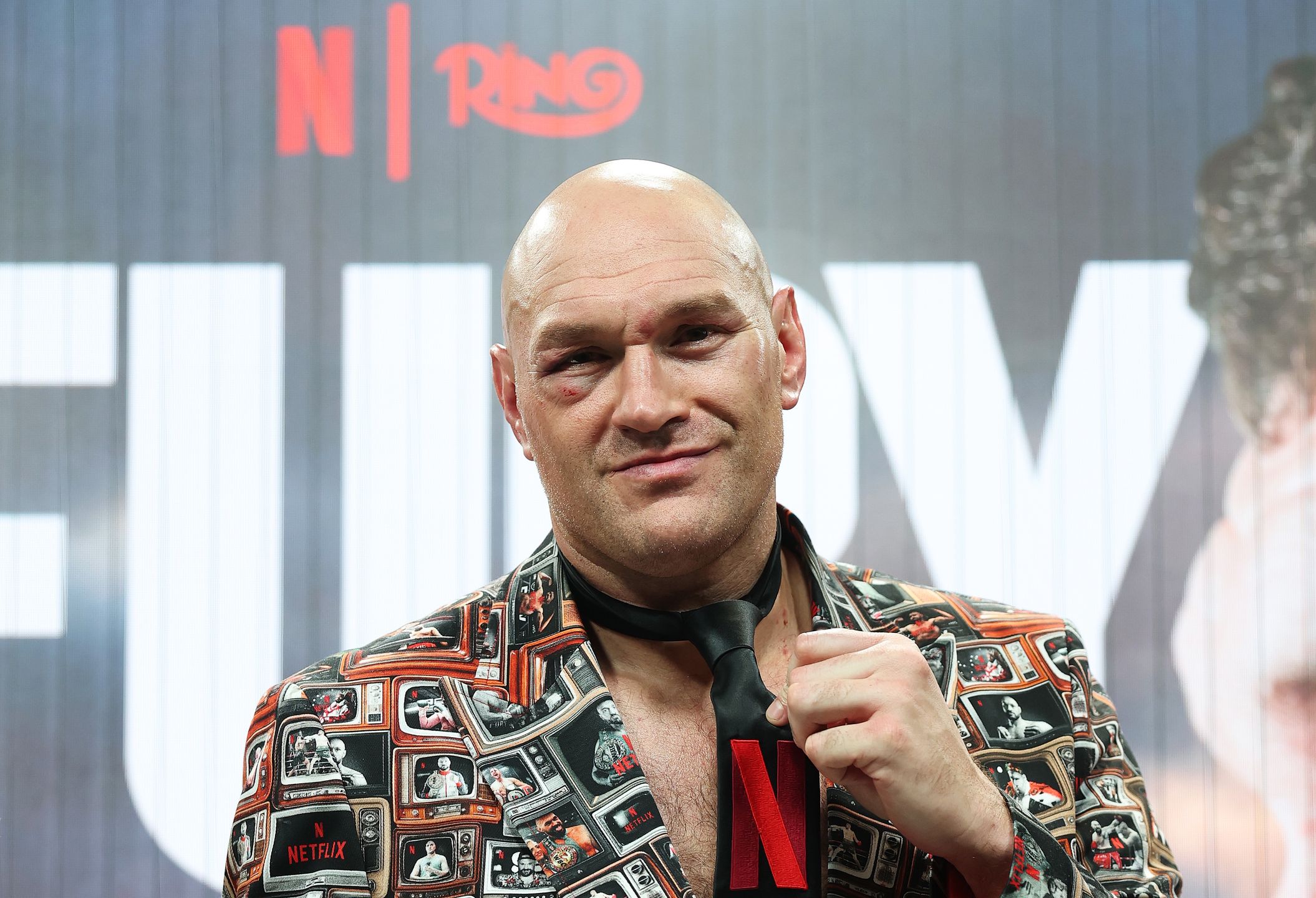 LONDON, ENGLAND - APRIL 11: Tyson Fury points to the Netflix logo on his tie as he speaks to the media during a press conference after his victory in the Heavyweight fight between Tyson Fury and Arslanbek Makhmudov at Tottenham Hotspur Stadium on April 11, 2026 in London, England. (Photo by Richard Pelham/Getty Images for Netflix)