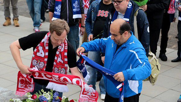 Przedstawiciele kibiców rosyjskich i polskich wspólnie składają wiązankę
