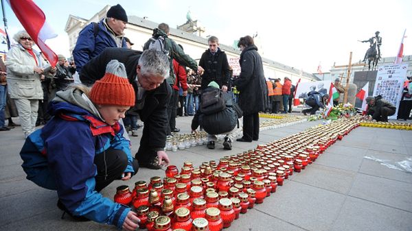 Ludzie składają kwiaty i zapalają znicze przed Pałacem Prezydenckim w Warszawie