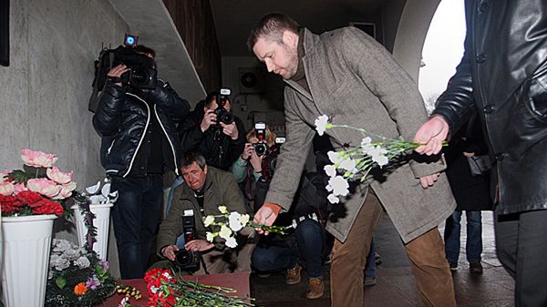 Kwiaty i znicze pod tablicą przy wejściu do stacji metra