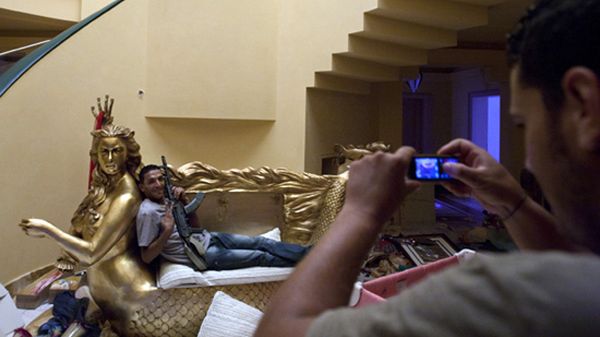 A rebel fighter poses for a photo as he sits on a two seater couch framed by a golden mermaid with the face of Aisha Gadhafi, the daughter of Libyan dictator Moammar Gadhafi, in her house in Tripoli, Libya, Wednesday, Aug. 24, 2011. A defiant Moammar Gadhafi vowed Wednesday to fight on "until victory or martyrdom," as rebel fighters tried to end scattered attacks by regime loyalists in the nervous capital.