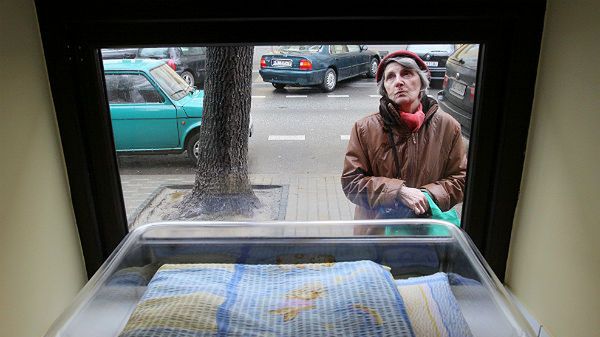 Kobieta zagląda do okna życia, gdzie można pozostawić niechciane noworodki