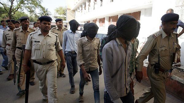 Policjanci eskortują mężczyzn podejrzanych o gwałt na Szwajcarce