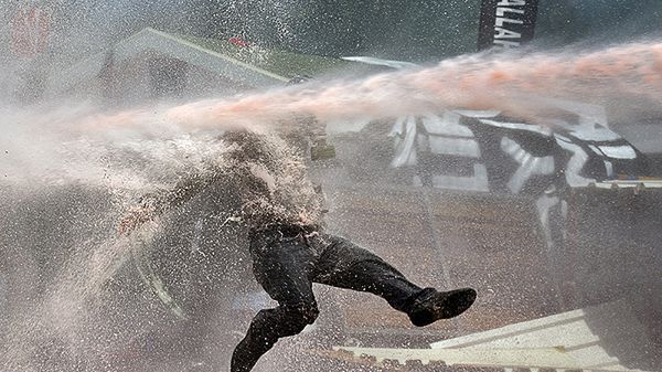 Jeden z demonstrantów w strugach wody z armatki wodnej