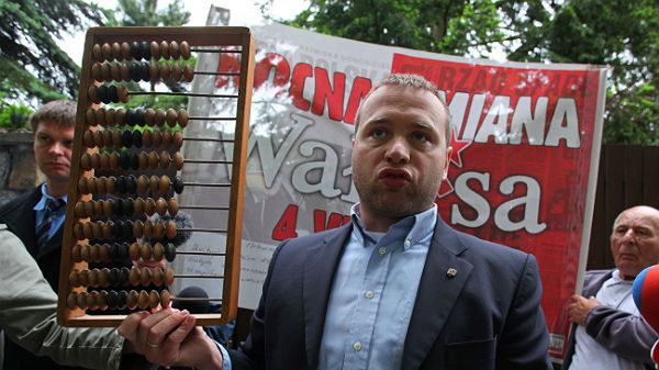 Michał Stróżyk pokazuje przyniesione dla Lecha Wałęsy liczydło