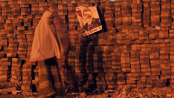 Kair, kobieta przechodzi obok plakatu z obalonym prezydentem Mursim