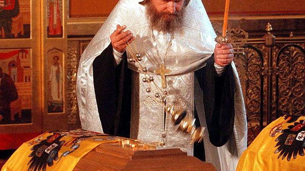 Pop odprawia modły nad trumnami ze szczątkami cara Mikołaja II i jego rodziny w czasie uroczystości pogrzebowych w Jekaterynburgu na Uralu.