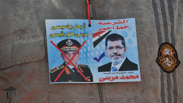 Zwolennik obalonego prezydenta z przekreślonym zdjęciem gen. al-Sisiego i portretem Mursiego