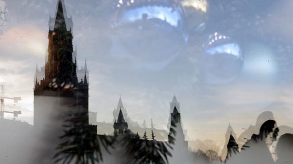 Kremlowska wieża Spasska odbija się w świątecznie ozdobionej witrynie sklepu na Placu Czerwonym