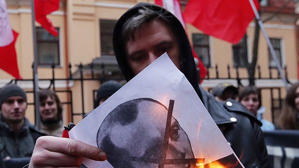 Protest przed konsulatem Ukrainy w Petersburgu. Demonstrant pali zdjęcie Stepana Bandery