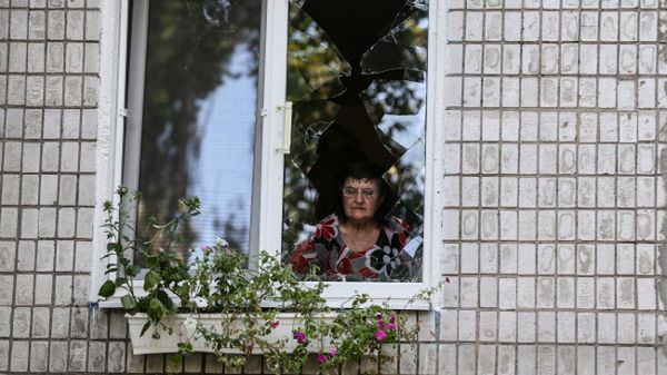 Mieszkanka Doniecka wygląda przez zniszczone podczas ostrzału okno