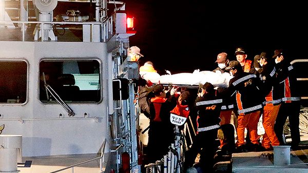 Ratownicy transportują ciało jednej z ofiar z zatopionego promu