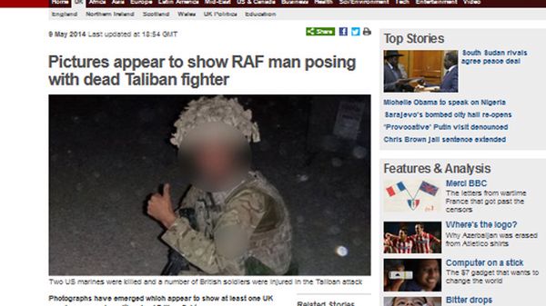 Na zdjęciu żołnierz pozuje przy zwłokach taliba