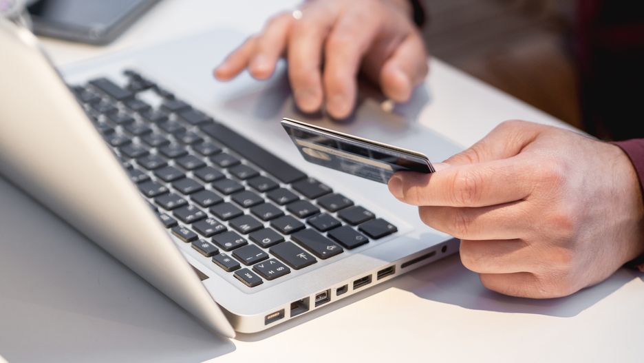 Man is using laptop to pay for online order by credit card. Online shopping or e-commerce. Contactless payment by wireless technologies.laptop, black Friday, payment, credit card, banking, Green Monday, Singles Day, sale, online, shopping, order, man, hand, pay, computer, wireless, contactless, technology, device, keyboard, type, smartphone, cellular, gadget, electronic, person, table