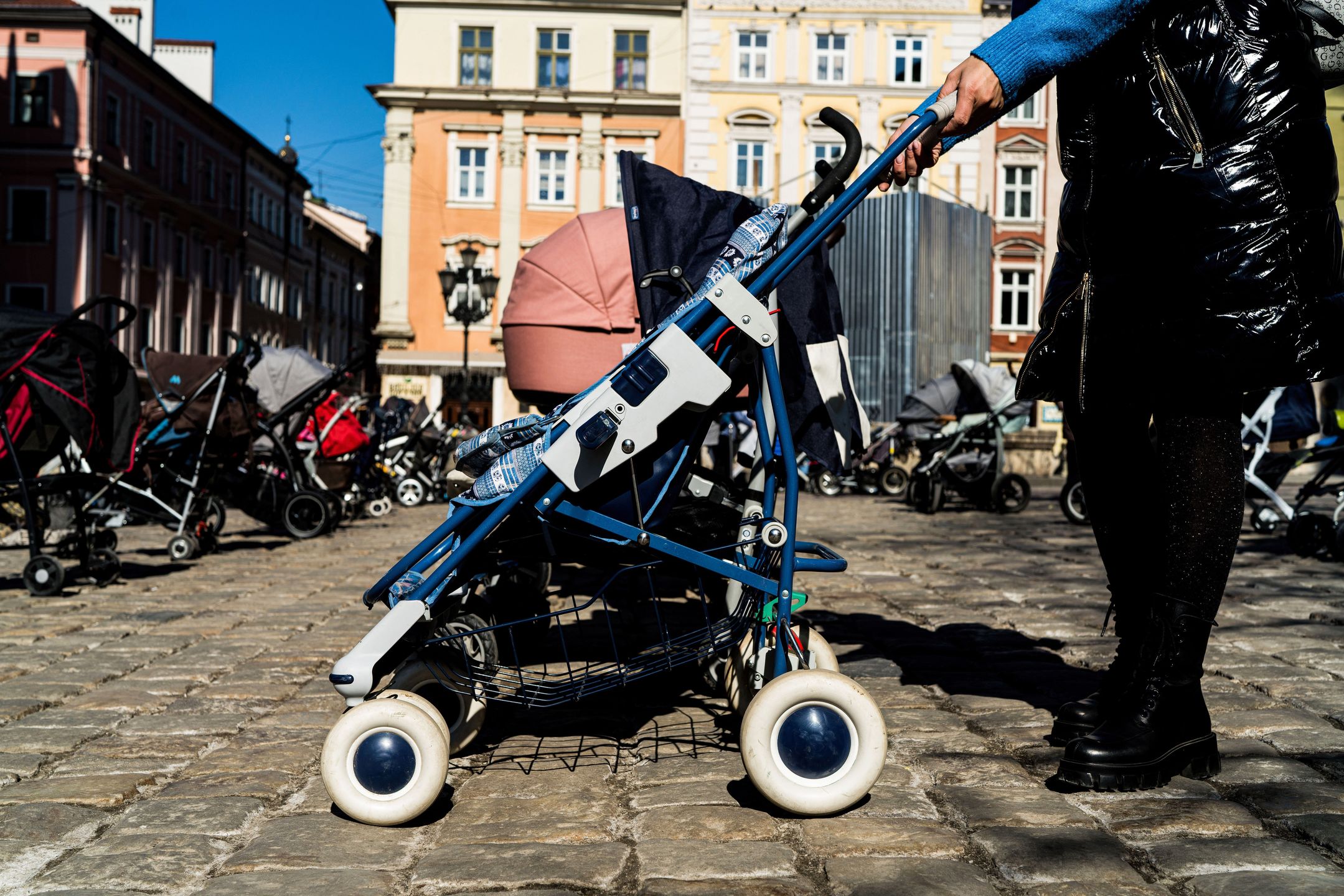 LVIV, UKRAINE - 2022/03/18: A woman seen with a stroller in Rynok Square during the memorial. 109 strollers have been arranged in several rows in Rynok Square in memory and honour of the 109 children killed by the war in Ukraine up to date. (Photo by Vincenzo Circosta/SOPA Images/LightRocket via Getty Images)