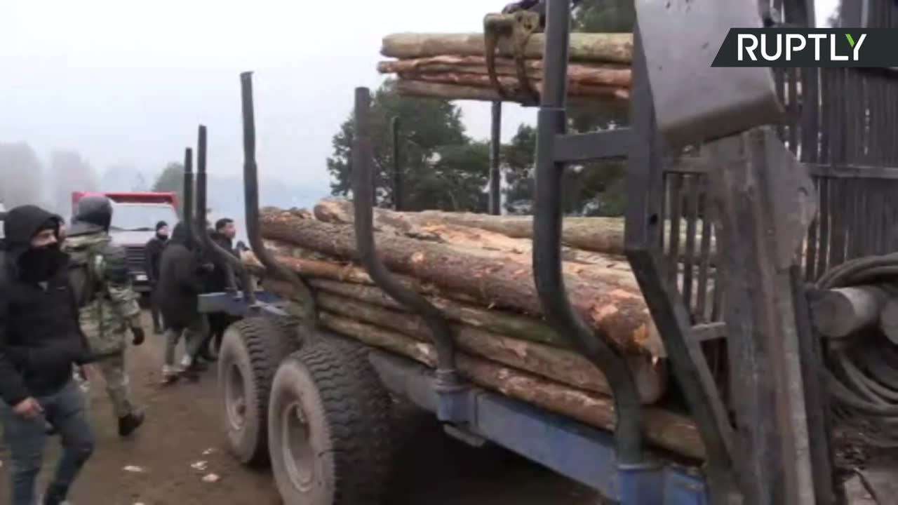 Długie kłody dostarczane do obozu dla uchodźców na Białorusi