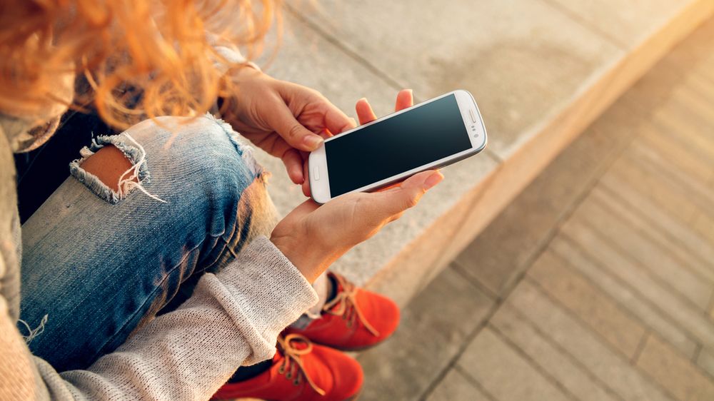 Kobieta trzymająca w ręku smartfon z depositphotos