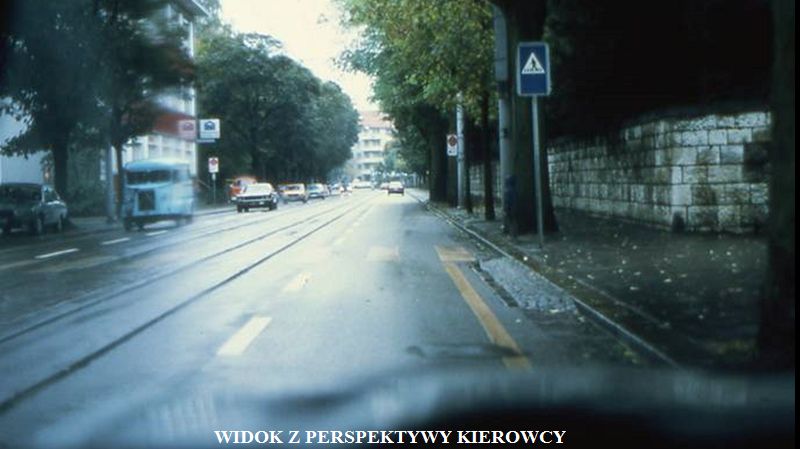 Przy przejściu dla pieszych stoi dziecko, lecz z powodu ciemnego ubioru jest praktycznie niewidzialne dla kierowcy.