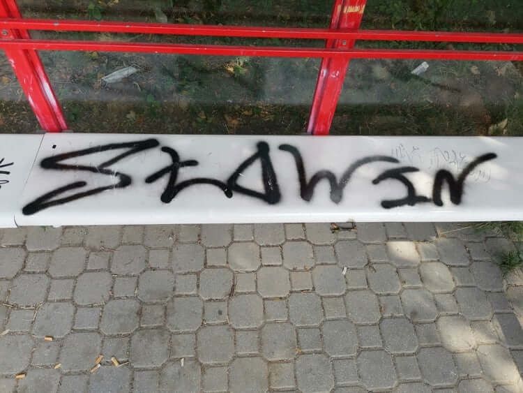napis graffiti na lawce wiaty przystankowej