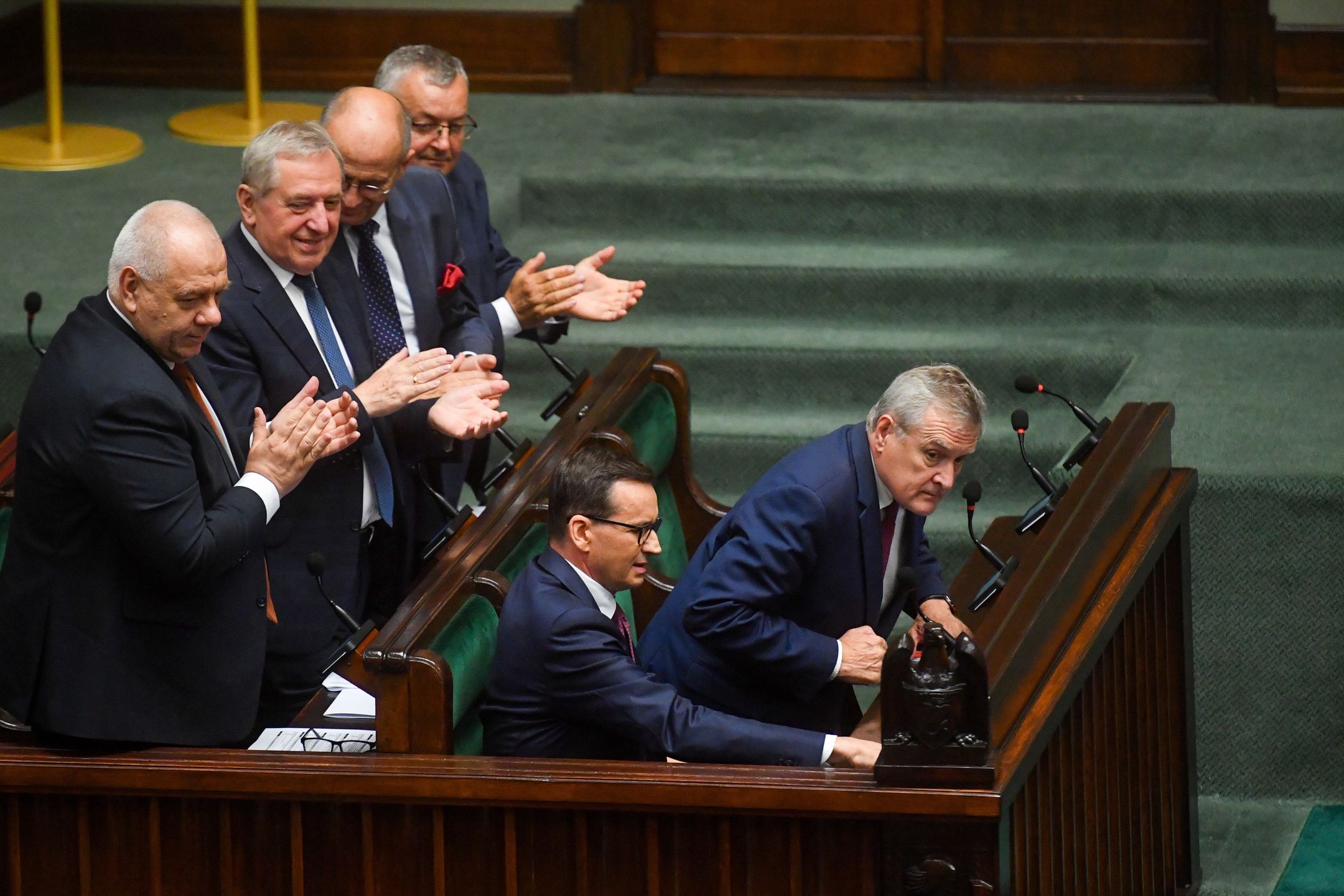 Warszawa, 13.07.2023. Premier RP Mateusz Morawiecki (2P), minister kultury i dziedzictwa narodowego Piotr Gliński (P), minister aktywów państwowych Jacek Sasin (L), minister - członek Rady Ministrów Henryk Kowalczyk (2L), minister spraw zagranicznych Zbigniew Rau (3L) oraz minister infrastruktury Andrzej Adamczyk (4L) na sali obrad Sejmu w Warszawie, 13 bm. Sejm przez aklamację przyjął uchwałę w sprawie oddania hołdu mieszkańcom polskich wsi w 80. rocznicę niemieckiego mordu w Michniowie. (jm) PAP/Piotr Nowak