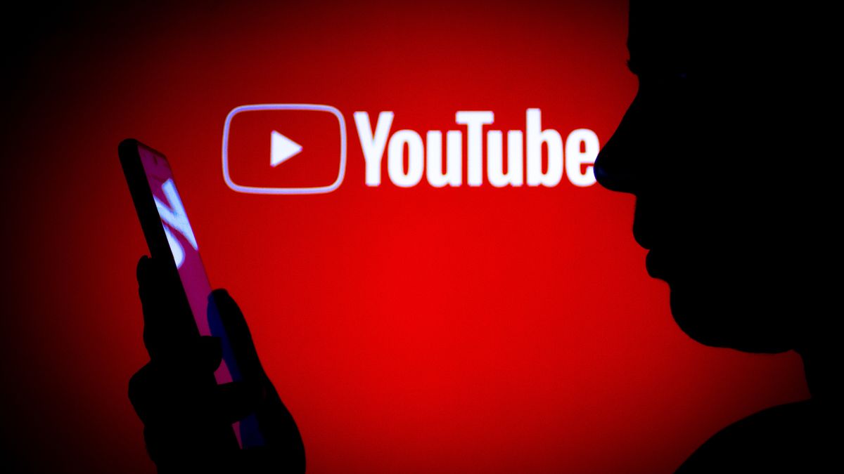 BRAZIL - 2022/03/14: In this photo illustration the YouTube logo seen in the background of a silhouette woman holding a mobile phone. (Photo Illustration by Rafael Henrique/SOPA Images/LightRocket via Getty Images)