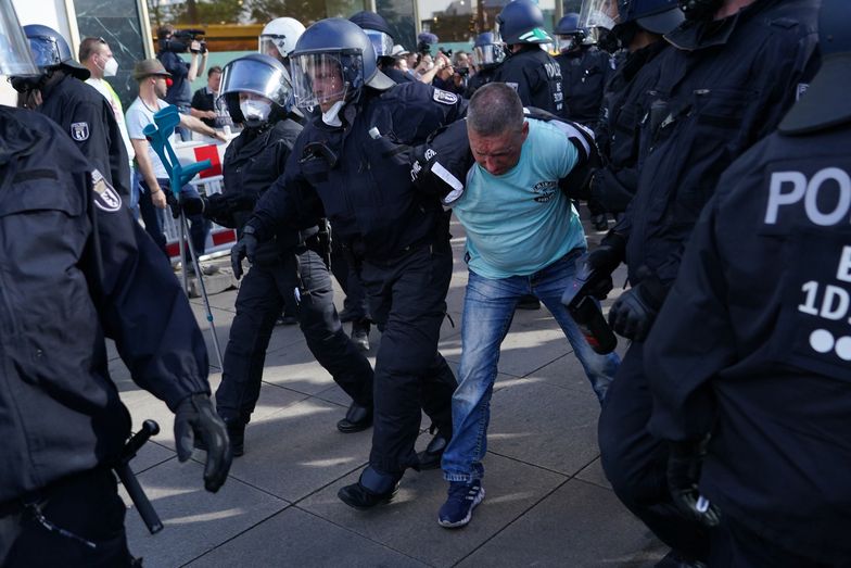 Policja zatrzymuje mężczyznę podczas nielegalnego zgromadzenia na Alexanderplatz.