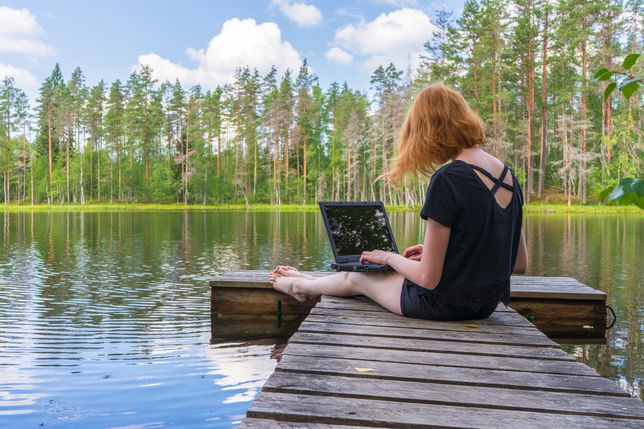 Cute ginger girl sitting on wooden planked footway and working with laptop in summer day against beautiful landscape of northern lake and forest. Freelance, work and travel concept. Karelia, RussiaCute ginger girl sitting on wooden planked footway and working with laptop in summer day against beautiful landscape of northern lake and forest. Freelance, work and travel concept. Karelia, Russia.freelance, freelancer, working, laptop, concept, outdoor, lady, girl, sitting, lake, attractive, authentic, background, beautiful, business, computer, enjoyment, female, forest, happy, hipster, internet, journey, landscape, leisure, lifestyle, natural, nature, north, notebook, person, planked footway, relaxation, remote, remotely, russian, shore, summer, technology, teenager, tourism, travel, traveler, using, vacation, water, woman, wooden, work, young