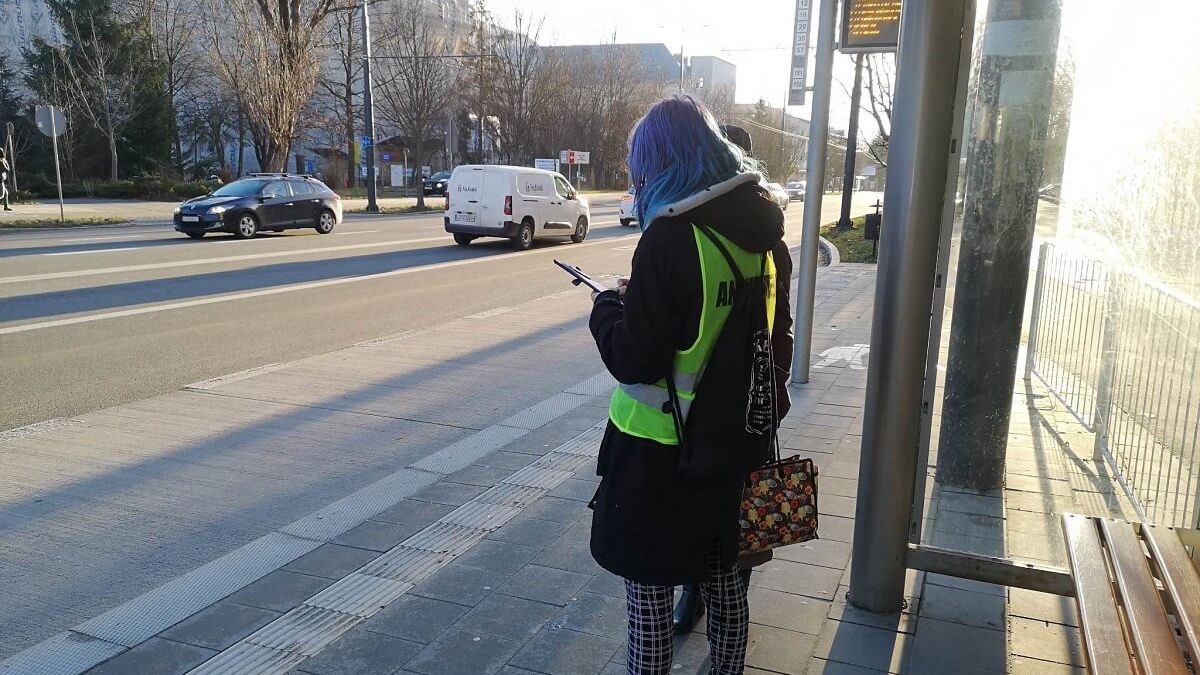 Ankieter na przystanku rozmawiający z pasażerem