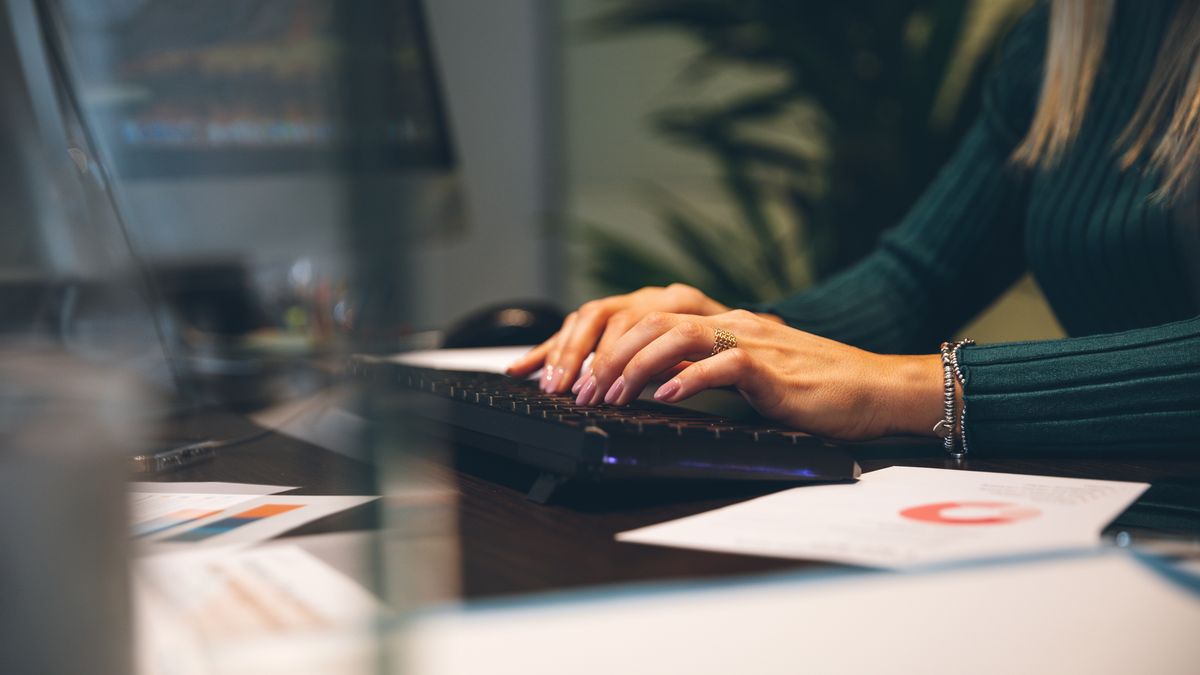 Woman at work typing on computer keyboard at the office.