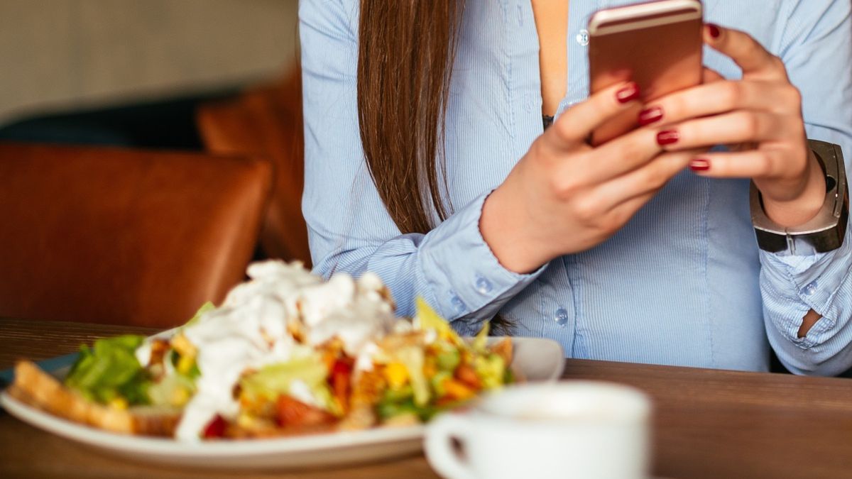 Kobieta trzymająca telefon nad talerzem z sałatką