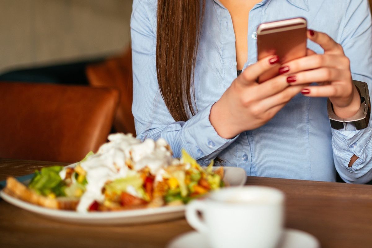 Kobieta trzymająca telefon nad talerzem z sałatką