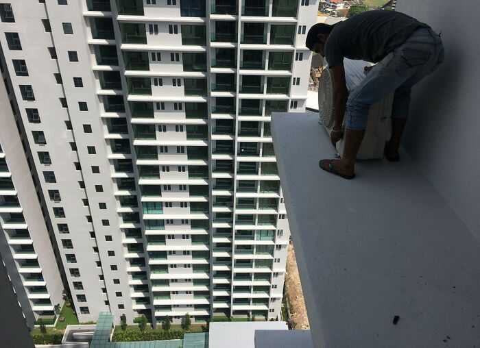 Pracownik naprawia klimatyzację na 24 piętrze.