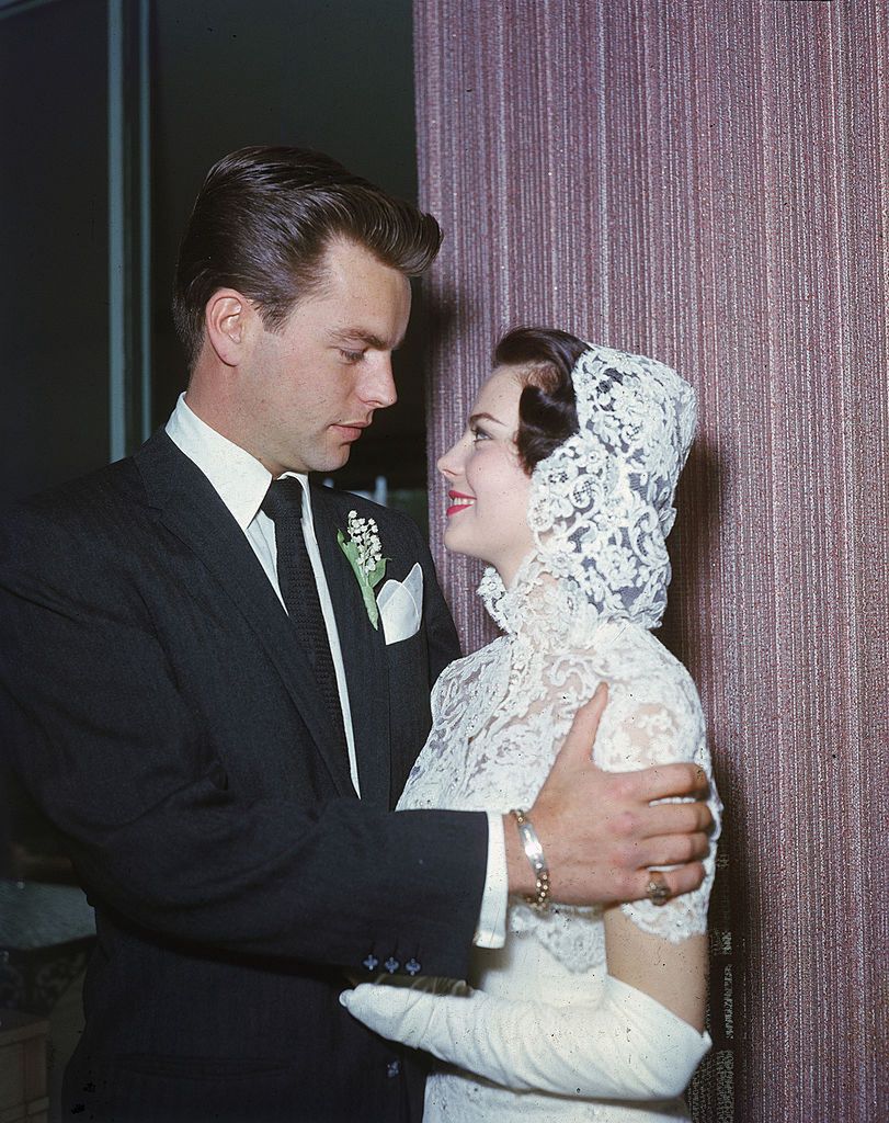Robert Wagner & Natalie Wood Wedding
American actor Robert Wagner, wearing a suit and tie with a corsage, and American actor Natalie Wood (1938 - 1981), wearing a white strapless wedding dress with a white lace hooded cape, embrace each other and smile on their wedding day, Scottsdale, Arizona, December 28, 1957. (Photo by Jack Albin/Getty Images)
Jack Albin
photograph lace color colour Marriage stars and family Personali