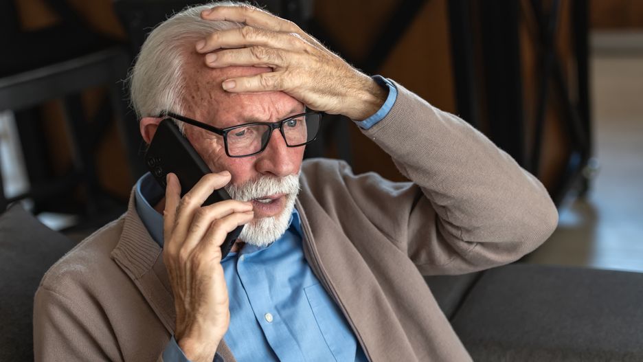 elderly, senior, old man, worried, stressed, phone call, emergency, concern, anxiety, problem, bad news, reaction, facial expression, home, indoor, glasses, beard, cardigan, blue shirt, distress, communication, mobile phone, talking, shocked, surprised, serious, elderly care, healthcare, crisis, fear, emotions, loneliness, retirement, aging, mature adult, senior citizen, thinking, decision-making, financial issues, scam, fraud, technology, worried expression, home interior, close-up, stressful situation, bad news reaction, confused, uncertainty