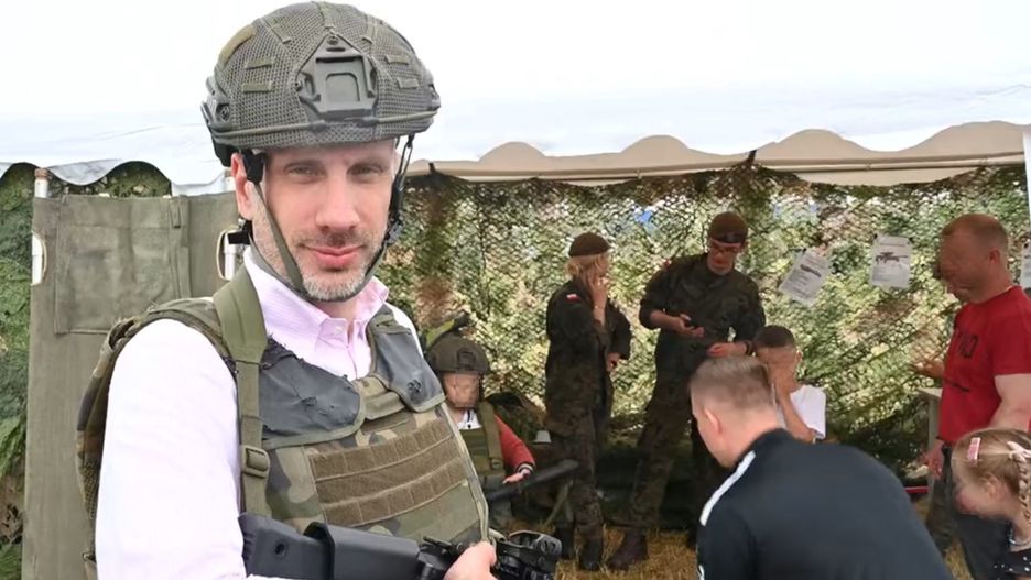 Janusz Kowalski z bronią, a obok rodzice z dziećmi