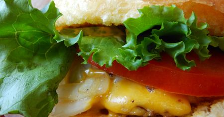 Powiększony cheeseburger z przyprawami, warzywami i szynką