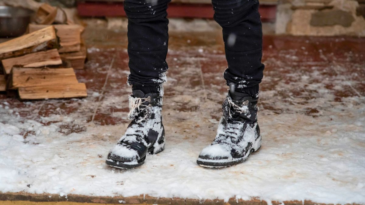 Kobieta stoi w ośnieżonych butach na ganku